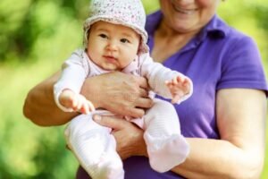 avo sorridente segurando maos da crianca