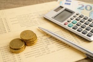 calculadora ao lado de contracheque e moedas