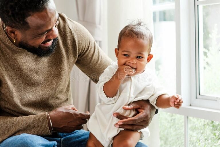 pai segurando bebe sorrindo em casa