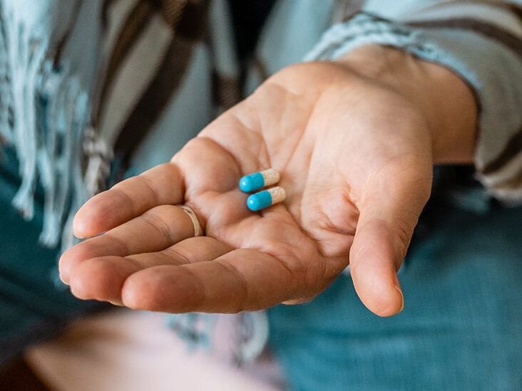 pessoa segurando carteira de trabalho e comprimidos