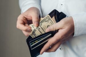 pessoa segurando carteira e dinheiro apos demissao